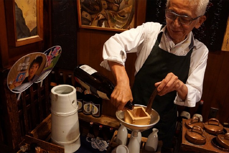 一合升できっちりと酒の量を計りながら徳利へ注ぐ