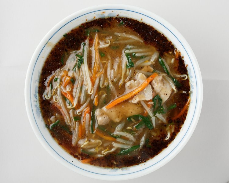 3種の油で炒めた焦がしネギが具のモヤシやニンジン、豚肉を囲む。麺は平打ちの卵麺。