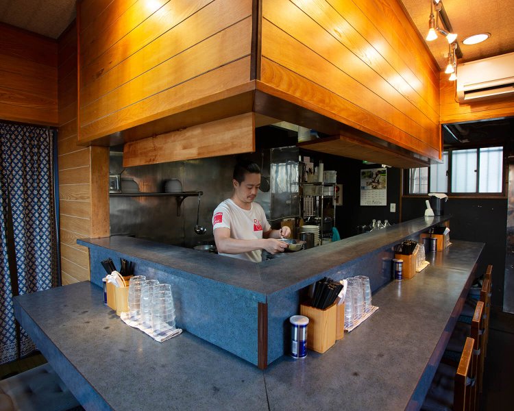 厨房に立つ店主の市原朋宏さん。