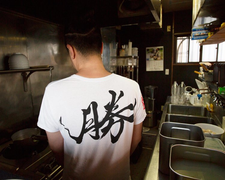 Tシャツには病気の際に友人が書いた「勝」の文字が。