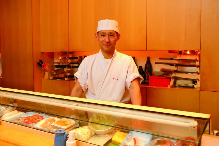 店主の加藤さん。長いカウンター席の奥で手際よく仕事をする。