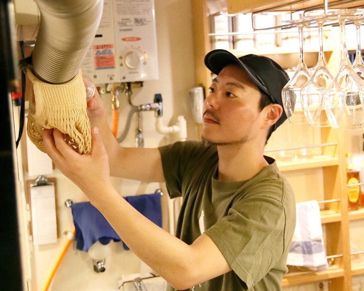 2階からの注文はパイプにカプセルを落とす独特な方式。注文を受け取る中村さん。