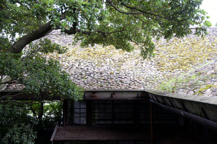 杉皮葺きに約４万個の石がびっしりと置かれた特徴的な石置屋根。