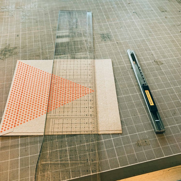 封筒上部をカットして、カッターで折り返し部分に折り目をつける作業。