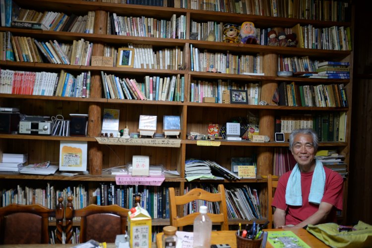 オーナーの長井三郎さん。フリースペースにぎっしりと本が並ぶ。