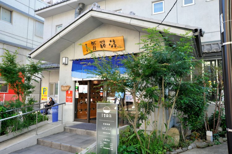 植え込みや瓦をのせた三角屋根が、昔ながらの銭湯の風情を漂わせる。