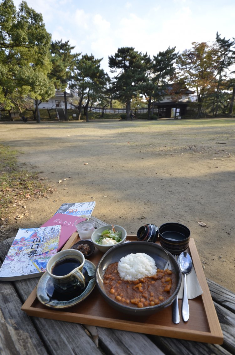 櫓（やぐら）門と櫓２棟に囲まれた本丸広場。テイクアウト可の城藤茶店のカレー850 円やコーヒー450 円、貸本（無料）でくつろごう。