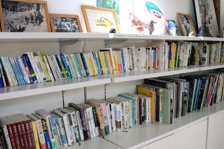 秋山郷や登山などの書籍が並ぶ本棚。学校で使われていたと思われる振り鐘も残る。