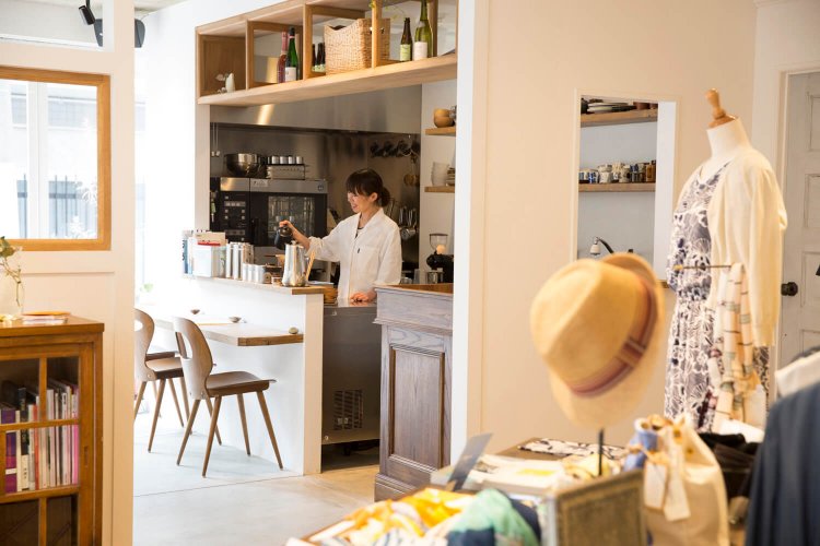 白衣姿で店に立つ大野さん。洋服店との間仕切りは窓の高さにこだわったという。