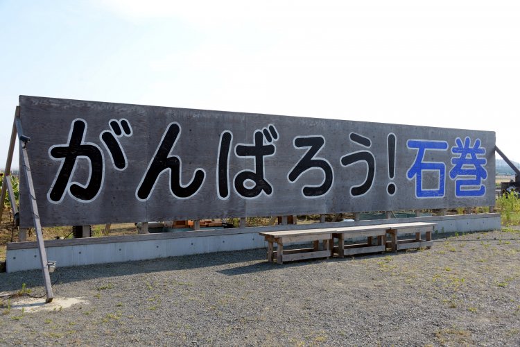 震災１ケ月後に建てられた看板のレプリカ。「石巻南浜津波復興祈念公園」（予定地）内にあり、そばに献花台も。