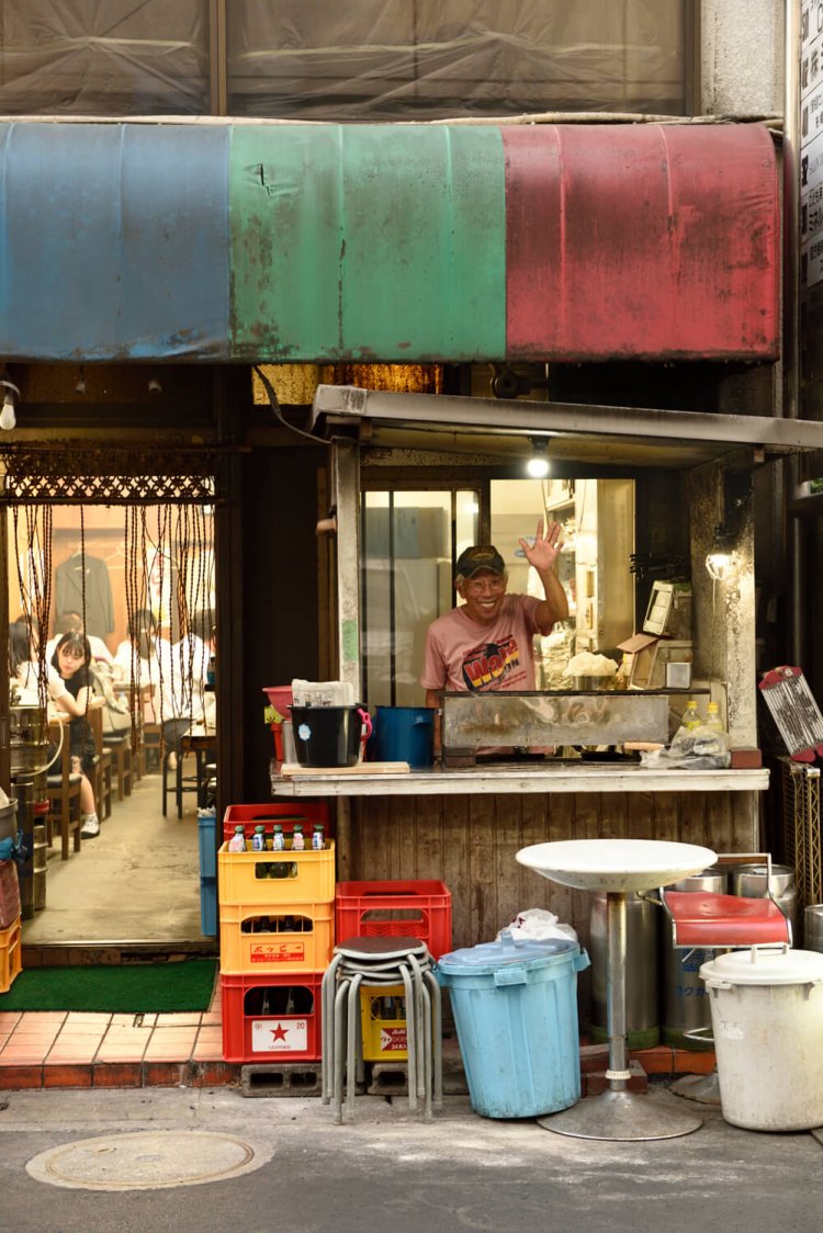 軒先で炭火を使って焼く津野田さん。前を通ると挨拶していく地元の人も。