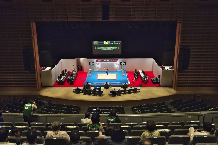 演技台に立つ選手の周りを審判員などがぐるりと取り囲む。左右の壁の外側は選手のウォーミングスペース。