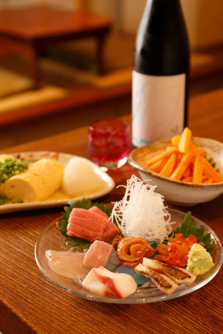 足立や浦和の市場から毎日仕入れる新鮮魚介の刺身盛合せや柿の山葵あえ（奥）などは、どれも地酒と相性よし。