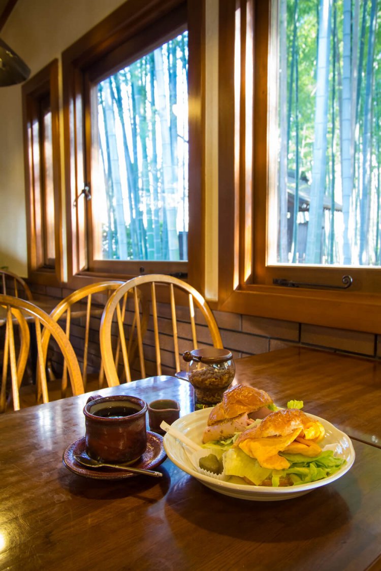 通常14時まで提供されているクロワッサンサンドセット1100円。ハムと卵の2種類でボリュームあり。独特な赤色のコーヒーカップは益子焼。額縁のような木の窓枠は内装で最もこだわった部分。