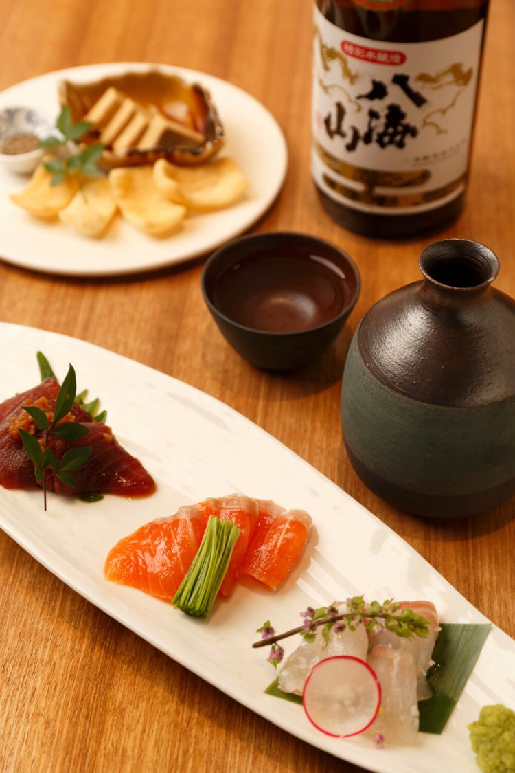 麹漬けお刺身3種盛り合わせ1100円は、醤油麹でマグロを、塩麹で白身魚や八海山サーモンを漬けたもの。八海山ねり粕使用 クリームチーズの味噌漬け715円、特別本醸造 八海山の燗。