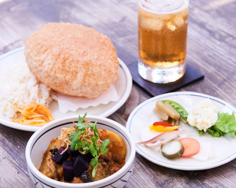 材木座の潮風で干した野菜をふんだんに使う風干し野菜カレー。風船のように膨らんだインドの大衆的なパン「プーリー」とともに。