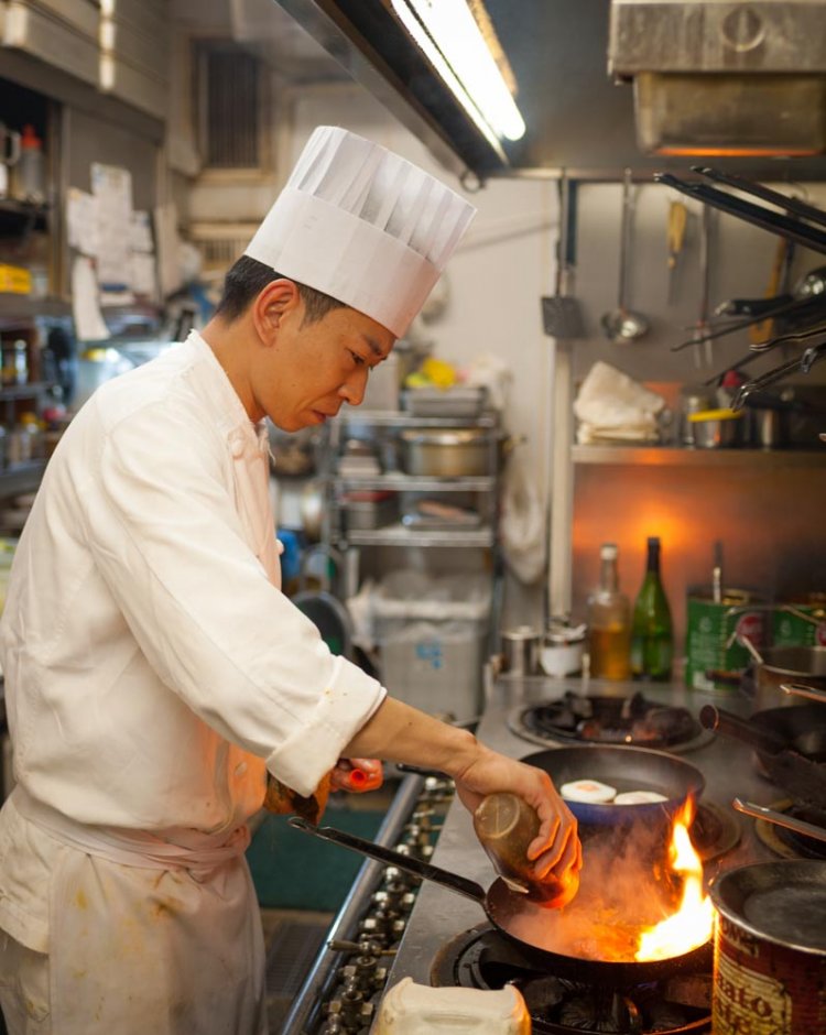 流れるような動きで調理する、コックの手塚清照さん。