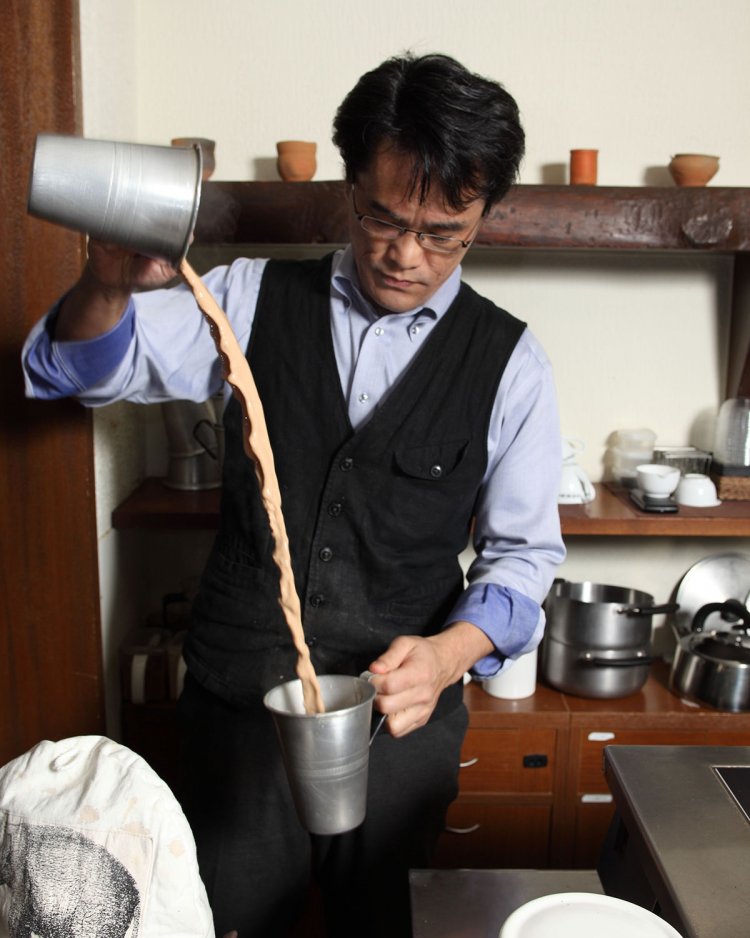 木の感触が落ち着く店内でチャイを注ぐ店主の水野さん。