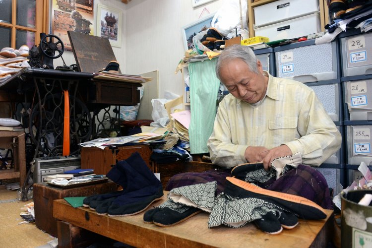 店舗を兼ねた作業場で手縫いする3代目の大和恵（しげる）さん。