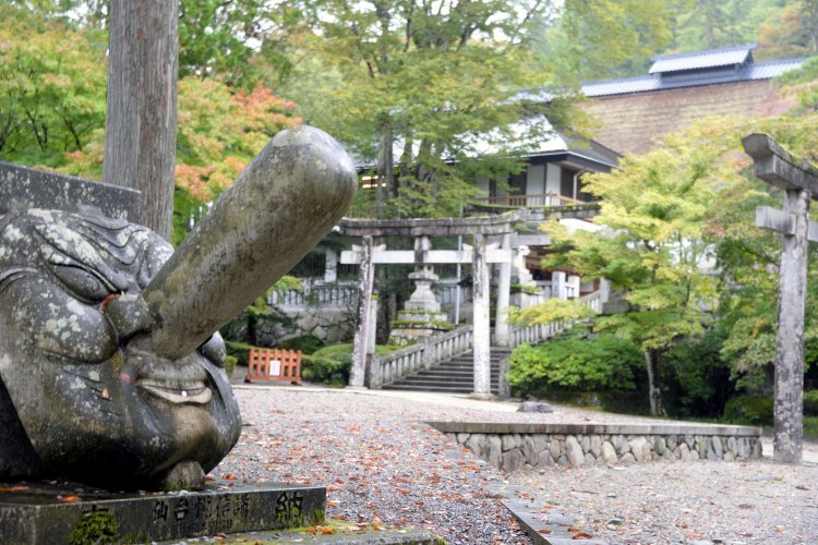 そこかしこに天狗の面が。奥は茅葺きの大拝殿。