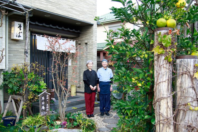 康雄さんと妻の君代さん。庭には四季折々の花が。