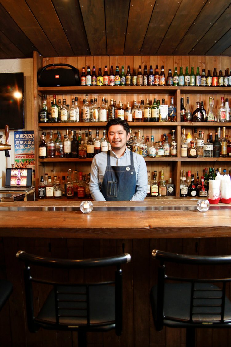 鴨下さん。棚には酒が並ぶ。