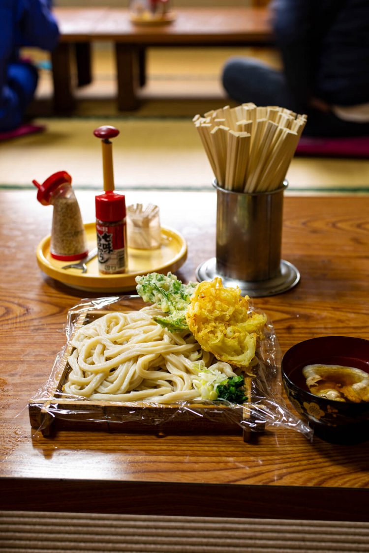 もりうどん500円と肉汁50円、玉ねぎと春菊の天ぷら各70円。食べきれないときは、持ち帰りできるよう麺の下にはラップ。