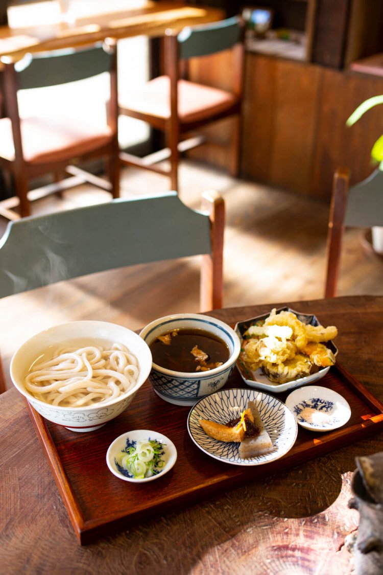 手打ちうどん並盛り。麺は冷水で締めるか、ずり揚げ（釜揚げ）での提供かを選べる。この日の天ぷらはユズの皮など地元食材が彩った。スパイシーなカレーうどん800円も人気。