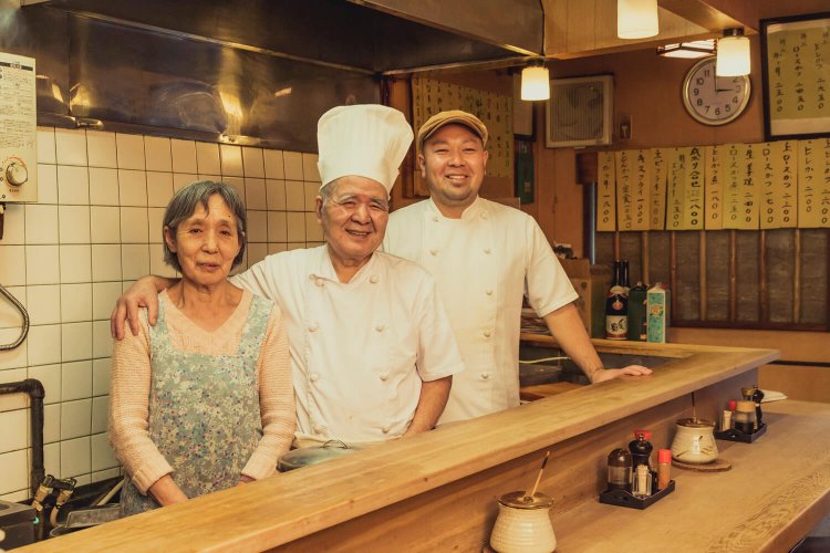 「しょうが焼きを食べると元気になる」と和子さん。初代節男さん（中央）、２代目隆さん。親子3人でのれんを守る。