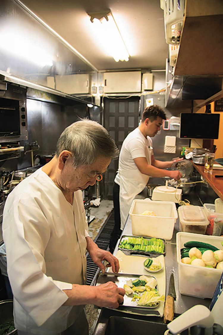 アキラさん（奥）と義父・憲昭さん。サバの味噌煮は憲昭さんが担当する。