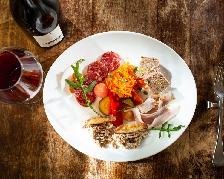 ワインを愉しむお肉屋さんの盛合せ2090円× 軽い赤。ワインはグラス880円～、ボトルは200種以上から選べる。