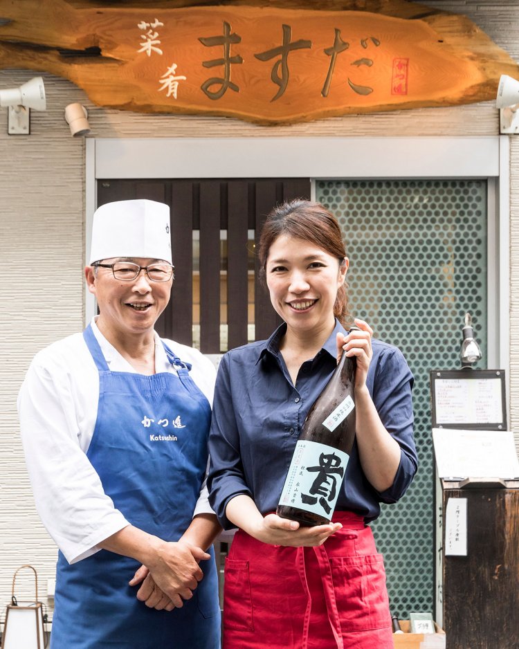 坪さん（左）と増田さん（右）。看板の字は増田さんのもの。