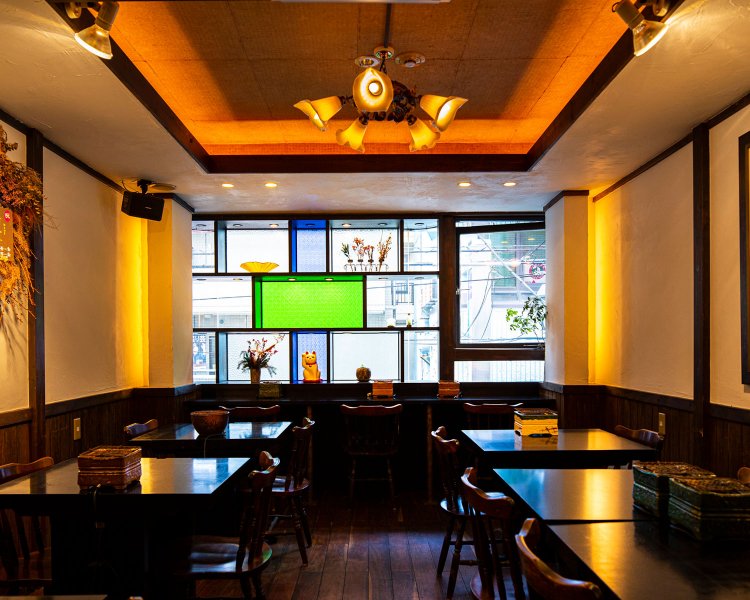 レトロなランプシェイドや窓にはめた色 ガラス、壁の絵が店内を彩る。