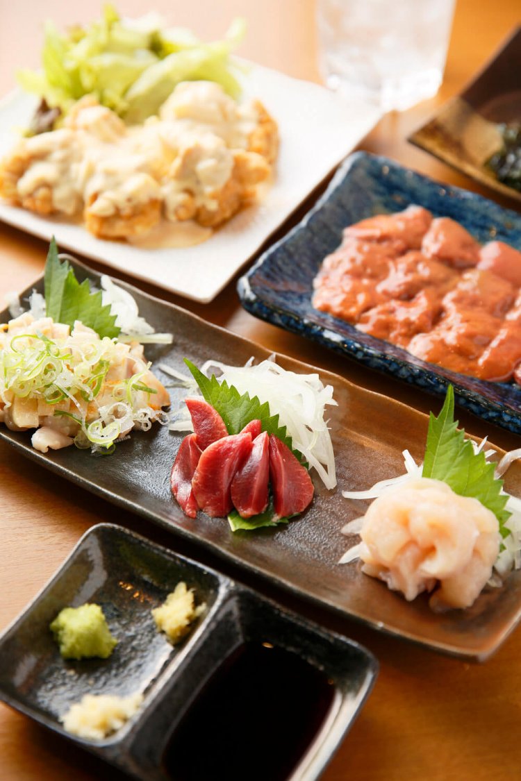 宮崎の甘口醤油が合う鶏刺し三点盛り1030円、赤鶏の白レバー刺し630円、母親からレシピを学んだ本場宮崎チキン南蛮550円。明月プレミアム400円。(全て税抜き)