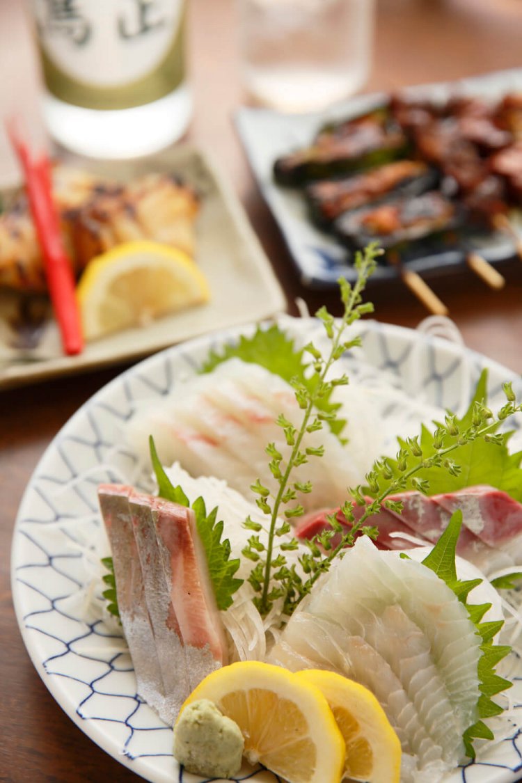 お刺し身盛合せ1320円。当日はヒラメや真ダイなど。メヌケの西京焼き660円、奥は店主が炭火で焼く名物のやきとり5本盛り合せ726円。麦焼酎鳥正ラベル440円。