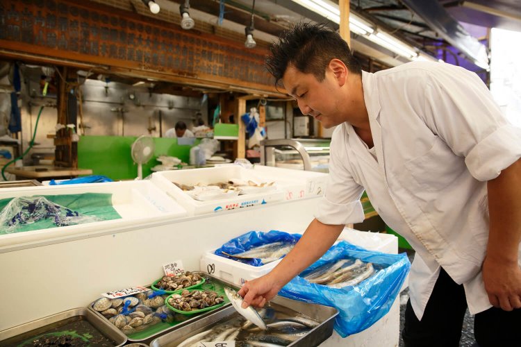 『魚次三』で魚を物色する料理長。