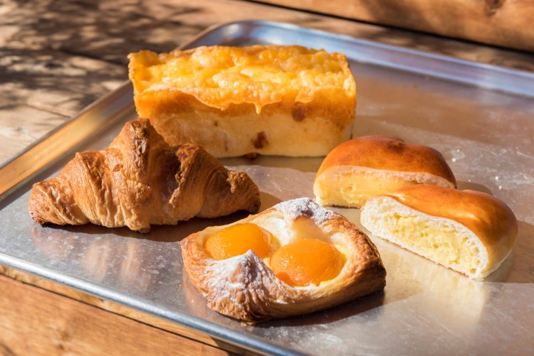 チーズチーズチーズ!!450円（奥）、クリームたっぷりクリームパン140円（右）、クロワッサン150円（左）、アプリコットのデニッシュ（期間限定製品）250円（手前）。