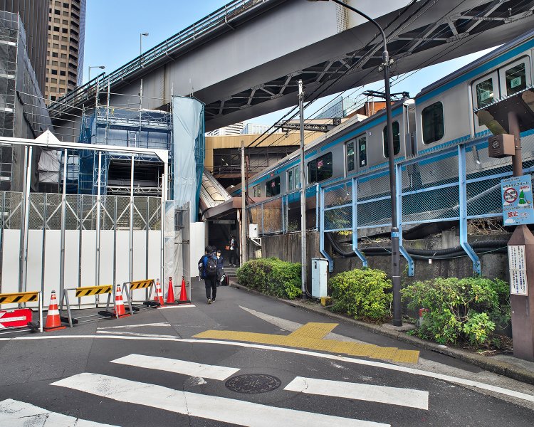 右に線路、頭上はモノレールに囲まれて3階分の高さを一気に上る金杉橋口。再開発工事で左側の道路が通行止め。その奥にあった南口出口が閉鎖されたために金杉橋口に乗降客が殺到する事態になった。