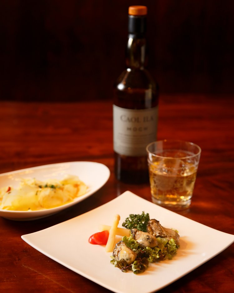 カキのオイル漬660円などママが手掛ける料理も絶品。ピート香の効いたカリラのモッホ12年1320円。