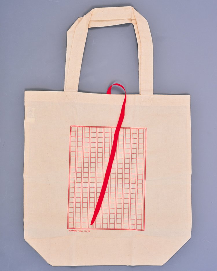 アトリエショップ限定の原稿用紙柄のオリジナルエコバッグ。しおりを模した紐でくるっとまるめてしまえる。原稿用紙に何か書き込んでカスタマイズしてもよし。990円。