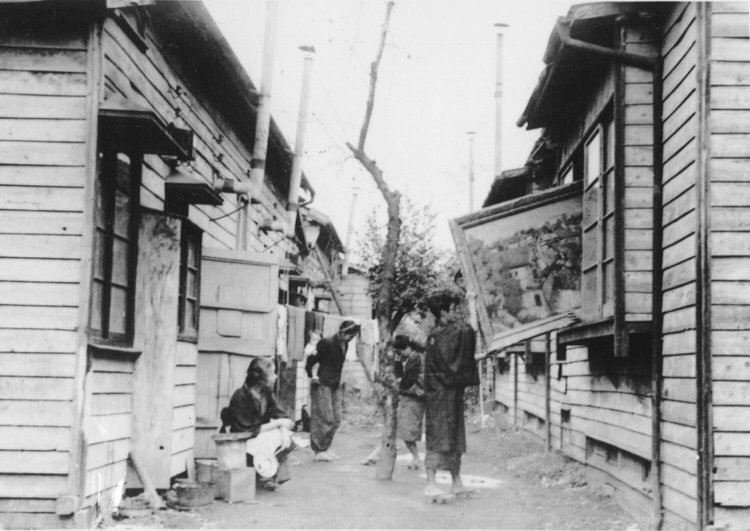 「さくらが丘パルテノン」のアトリエの窓から絵を出そうとしている様子。2軒続きの長屋になっている。（アトリエ村外観　1948年撮影　榑松正利氏提供）