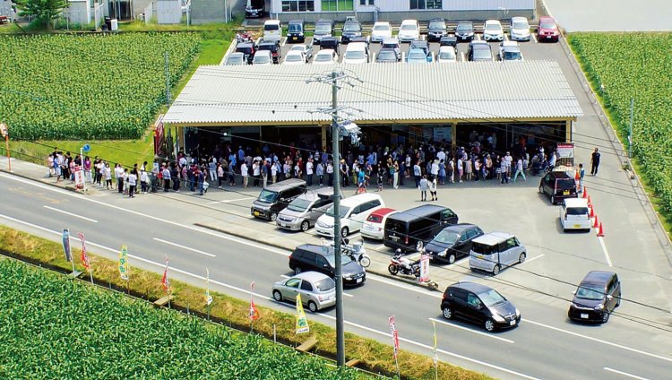 トウモロコシ畑に囲まれた直売所。早い人は朝4時ごろから並んでいる。