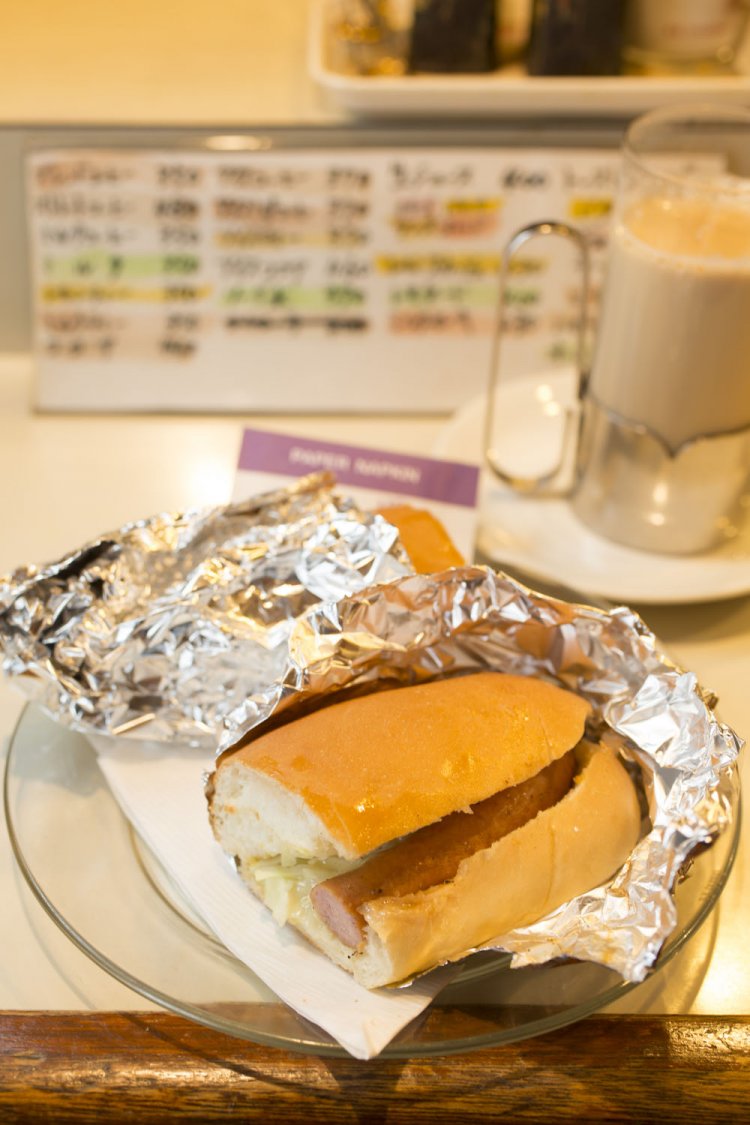 銀紙をむけば、ホットドッグ280円がお目見え。鍋で温めたミルクが多めのミルクコーヒー350円にも和む。
