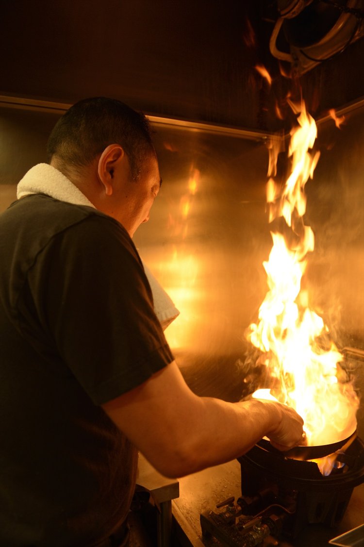 火柱を上げて鍋をあおる伊藤さん。