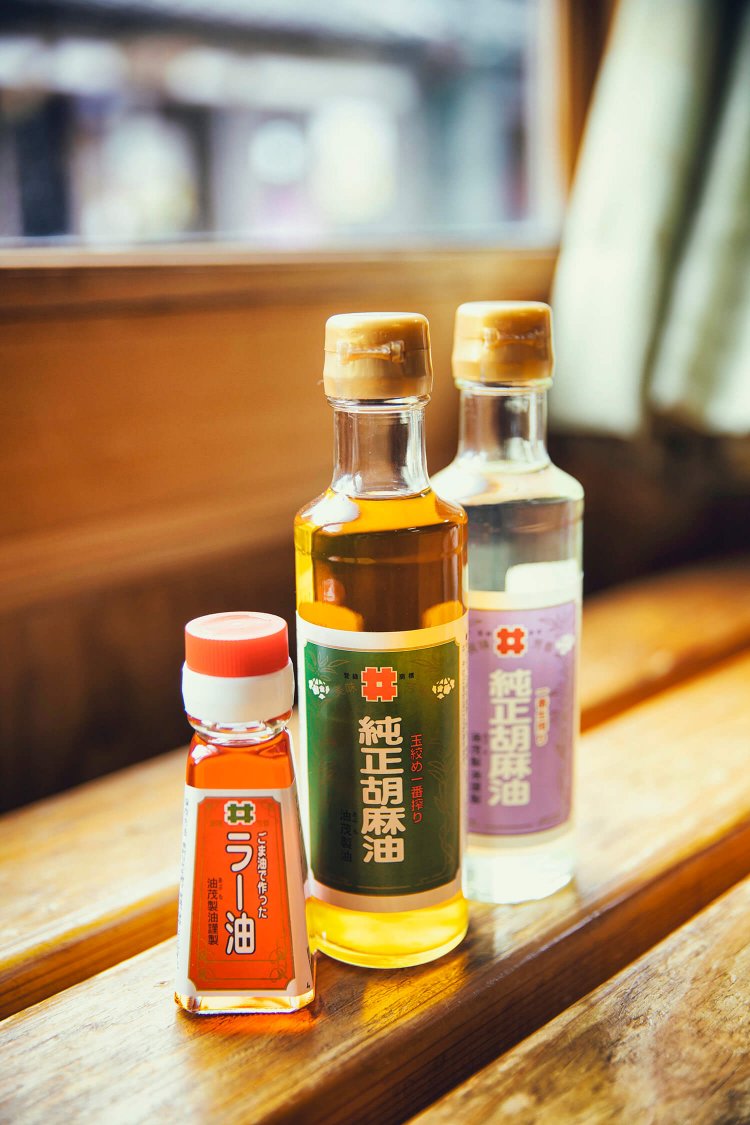 ごま油を基調に8種の香辛料を大鍋でじっくり溶かし出した「ごま油で作った ラー油」400円、伝統技術の玉絞め圧搾による「玉絞め一番搾り ごま油」330ｇ 1000円。ごま本来の旨味が味わえる「一番生搾り ごま油」 330ｇ 1000円。