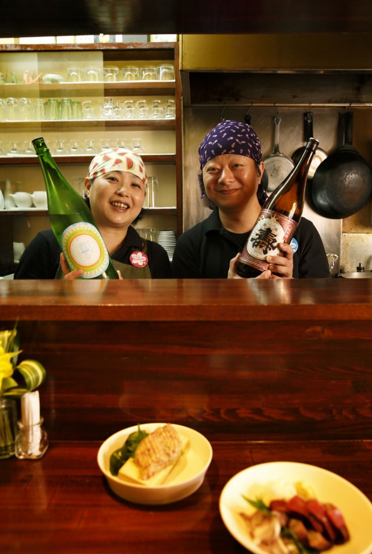 夫婦の温かい人柄も魅力。貴子さんが持つ『磐城壽 甦る 純米吟醸』600円(7勺)は同級生が醸した酒。