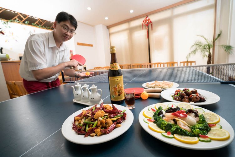 鄭さんの卓球の腕前はかなりのもの。手前左から、鶏肉の辛味炒め968円、三種海鮮炒め1078円、黒酢酢豚968円、焼き餃子（5個）418円。※通常卓球台での食事は不可。