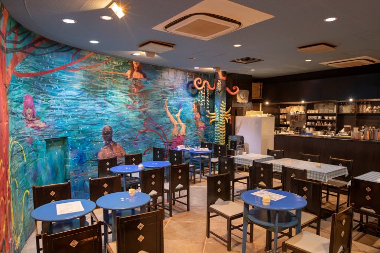 曲線の壁の絵は城戸真亜子さん作「幸せの予感」。今も制作中だ。