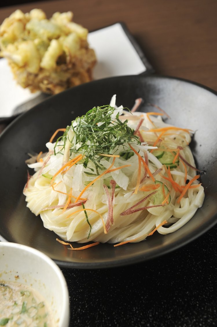 シソ、タマネギ、みょうが、キュウリ、ニンジンをのせた冷たいうどんを特製ゴマだれにつけて食す、夏の人気限定メニュー。
