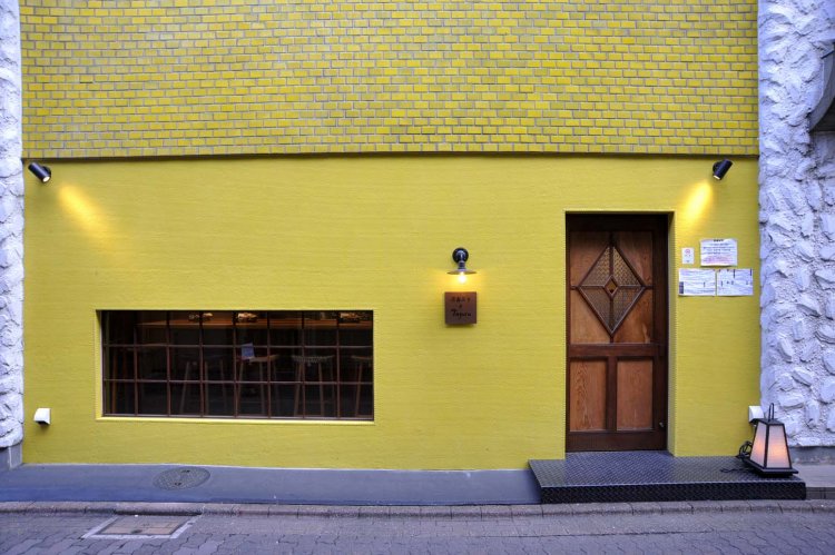 辛子色の外壁に、電球に照らされた看板がほんのりと浮かぶ。